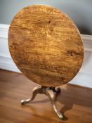 A George III oak circular tripod table, diameter 90 cm.