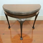 An early 20th century mahogany demilune turnover top card table on claw and ball feet, width 81 cm.