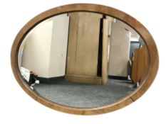 An early 20th century oak bevelled oval mirror, width 78 cm.