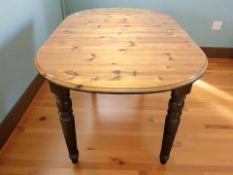 A modern pine extending oval dining table with internal leaf and a set of four spindle back chairs.