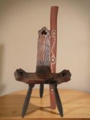 A rustic pine tripod stool and a painted didgeridoo.