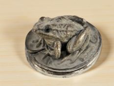 A small filled silver paperweight surmounted by a frog, diameter 3.5 cm.