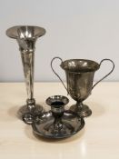 A loaded silver bud vase, a small trophy and a chamber stick.