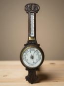An early 20th century carved oak aneroid barometer.