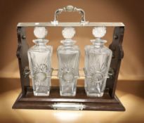 An oak and silver-plate Tantalus with three decanters,
