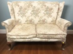 A 20th century wingback two seater settee in floral upholstery,