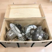A vintage trunk containing industrial light fittings.