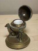 A Victorian brass ink well surmounted by three dogs, with ceramic liner, height 12 cm.