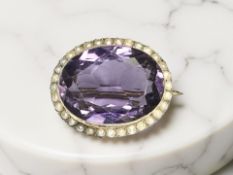 An antique 9ct yellow gold brooch set with an amethyst and seed pearls, width 26 mm.