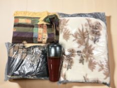 A group of woolen blankets and a glazed earthenware vase.