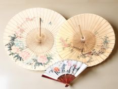 Two oriental lacquered parasols and a large hand fan.