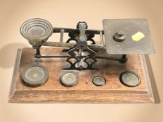A set of 19th century oak and brass balance scales with weights, width 27 cm.