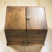 A Victorian oak sloped front correspondence box containing a glass ink well and two ball point pens,