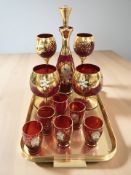 A gilt ruby glass decanter, matching pair of champagne glasses,