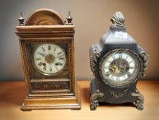 A late 19th century patinated metal mantel clock with visible escapement and a further beech cased