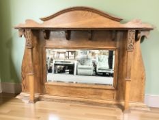 An Arts & Crafts carved and stained oak overmantel mirror,