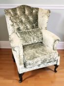A wing back armchair in buttoned plush fabric