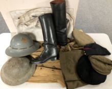 A group of tin helmets, other military hats and clothing, pair of canvas breeches,