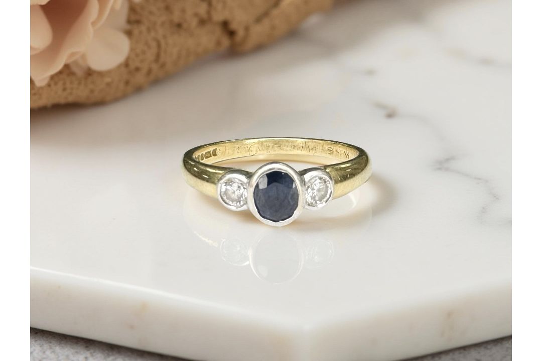 An 18ct yellow gold sapphire and two stone diamond ring, size M/N.