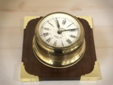 A ship's style brass cased clock on wooden backing signed President