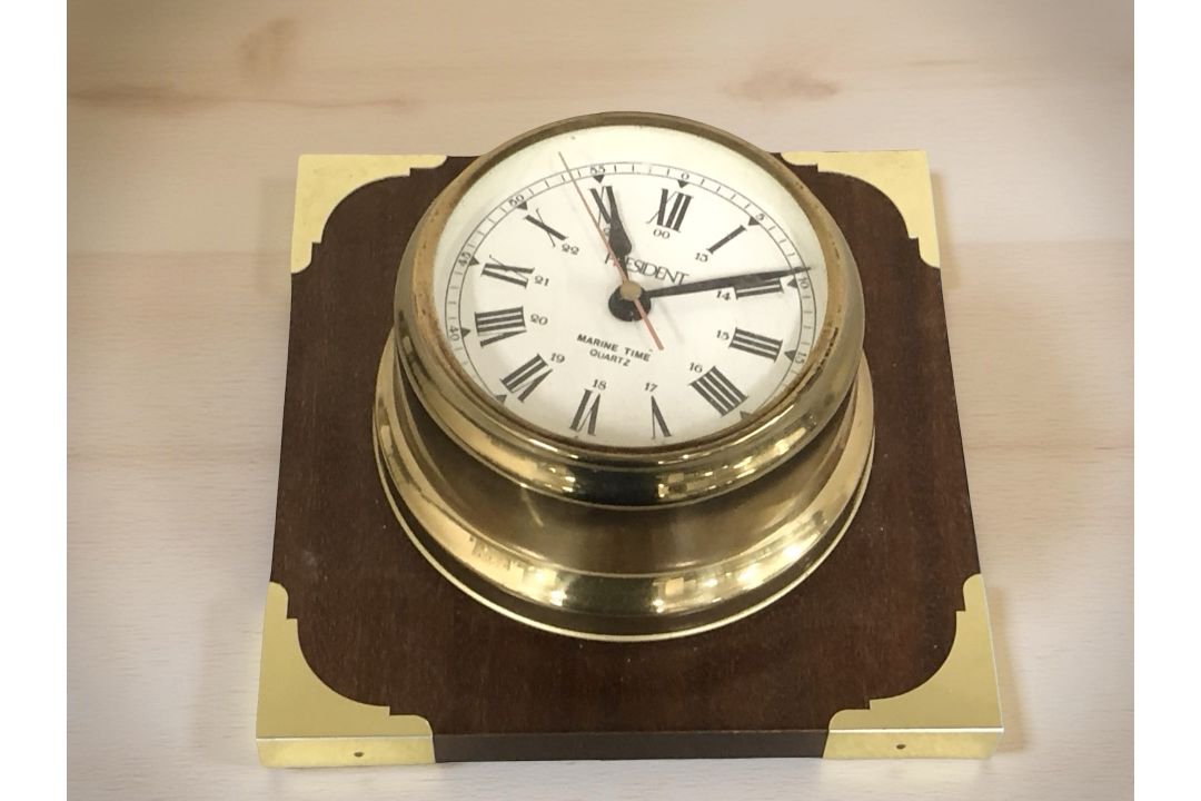 A ship's style brass cased clock on wooden backing signed President