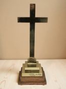 A brass crucifix on stepped oak plinth,