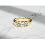 An 18ct yellow gold three stone tanzanite diamond ring, the central diamond approximately 0.