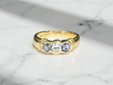 An 18ct yellow gold three stone tanzanite diamond ring, the central diamond approximately 0.