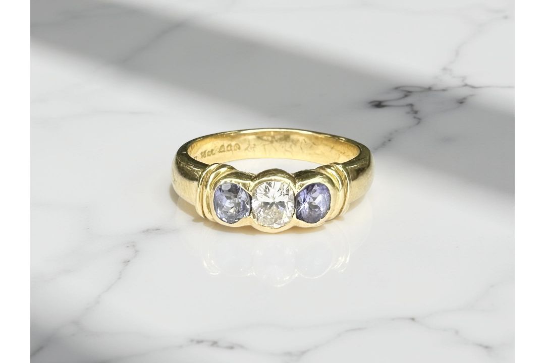 An 18ct yellow gold three stone tanzanite diamond ring, the central diamond approximately 0.