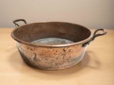 A 19th century copper twin handled pot, overall 60 cm wide.