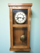 A continental oak cased wall clock with enameled dial, with pendulum and key, height 56 cm.