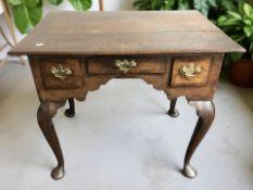A George III oak and walnut three drawer low boy, on cabriole legs terminating in pad feet,