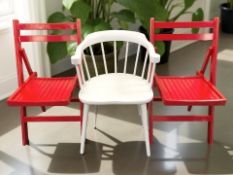 A pair of red painted folding wooden chairs and a further white spindle back chair.