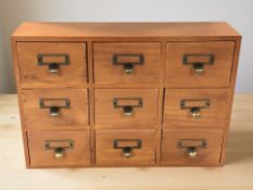 A reproduction bank of nine drawers with brass pull handles, height 26 cm.