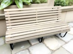 A painted wooden bench on curved metal supports,