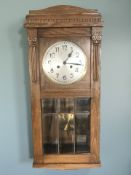 An early 20th century oak eight day wall clock with silvered dial, with pendulum and key,