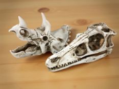 Two replica composition dinosaur skulls, length 17 cm.