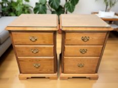 A pair of reproduction three drawer bedside chests, with plate glass tops,