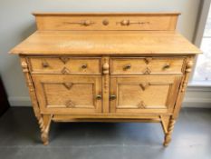 An Edwardian oak sideboard fitted cupboards and drawers, raised on barley twist legs,