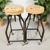 A pair of industrial style metal stools with hessian seat covers raised on castors, height 78 cm.