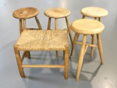 A set of four pine tripod stools and a further cane seated stool.