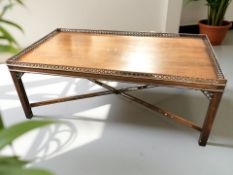 A reproduction mahogany coffee table with galleried top and X shaped under stretcher,