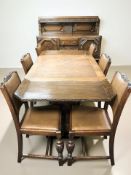 A 1920's heavily carved oak dining room suite comprising a pull-out extending dining table,