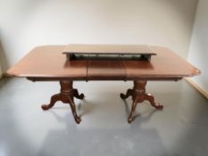 A reproduction mahogany effect twin pedestal extending dining table with two leaves,