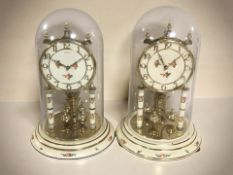 A pair of Kundo brass clocks under glass domes,
