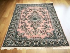 An Iranian-design rug on pink ground,