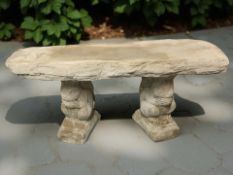 A rustic concrete garden bench on squirrel supports,