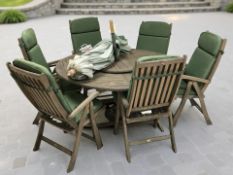 A stained teak circular garden patio table with central parasol,