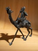 An African bronze sculpture of a figure riding a camel,