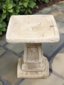 A concrete square bird bath,